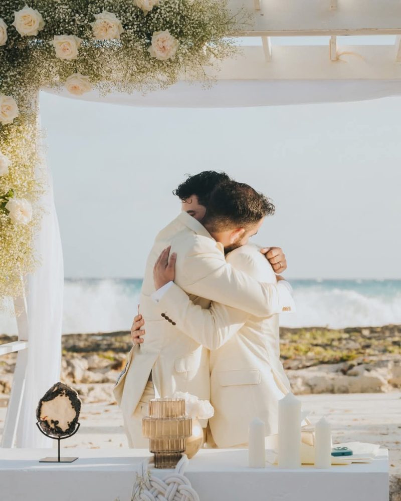 Novios bajo el arco floral frente al mar
